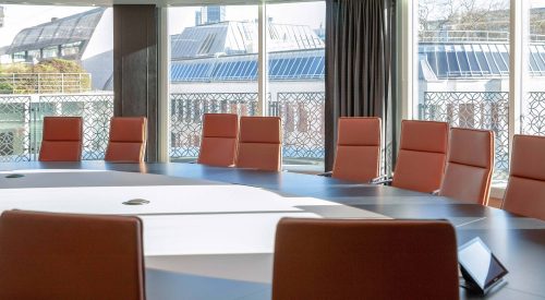 Board Room in ICG's London office, with seats around a large table and other buildings seen out of the window beyond
